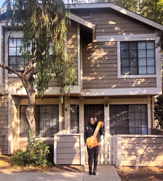 Hispanic homeowner in front of her new home