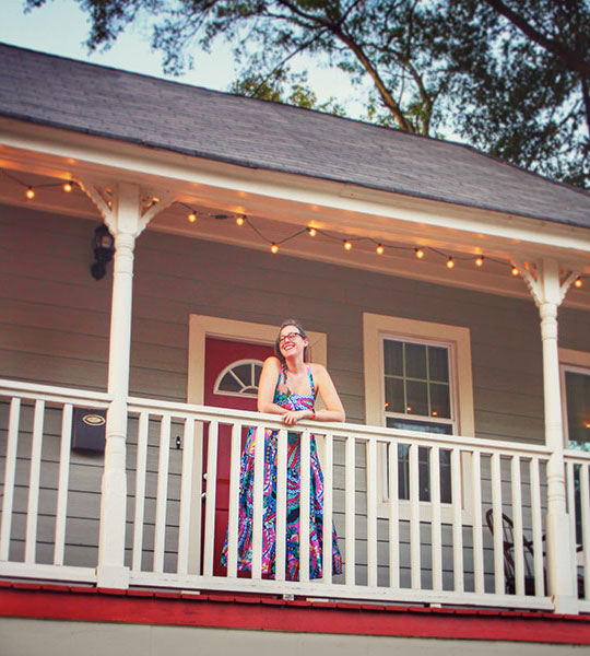 Photo of young woman standing on her home's porch